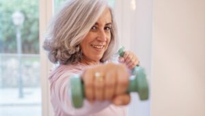 Eine Frau beim Hanteltraining zu Hause. (c) AdobeStock