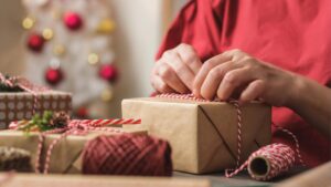 Die Hände einer älteren Frau, die ein Geschenk verpackt. (c) AdobeStock